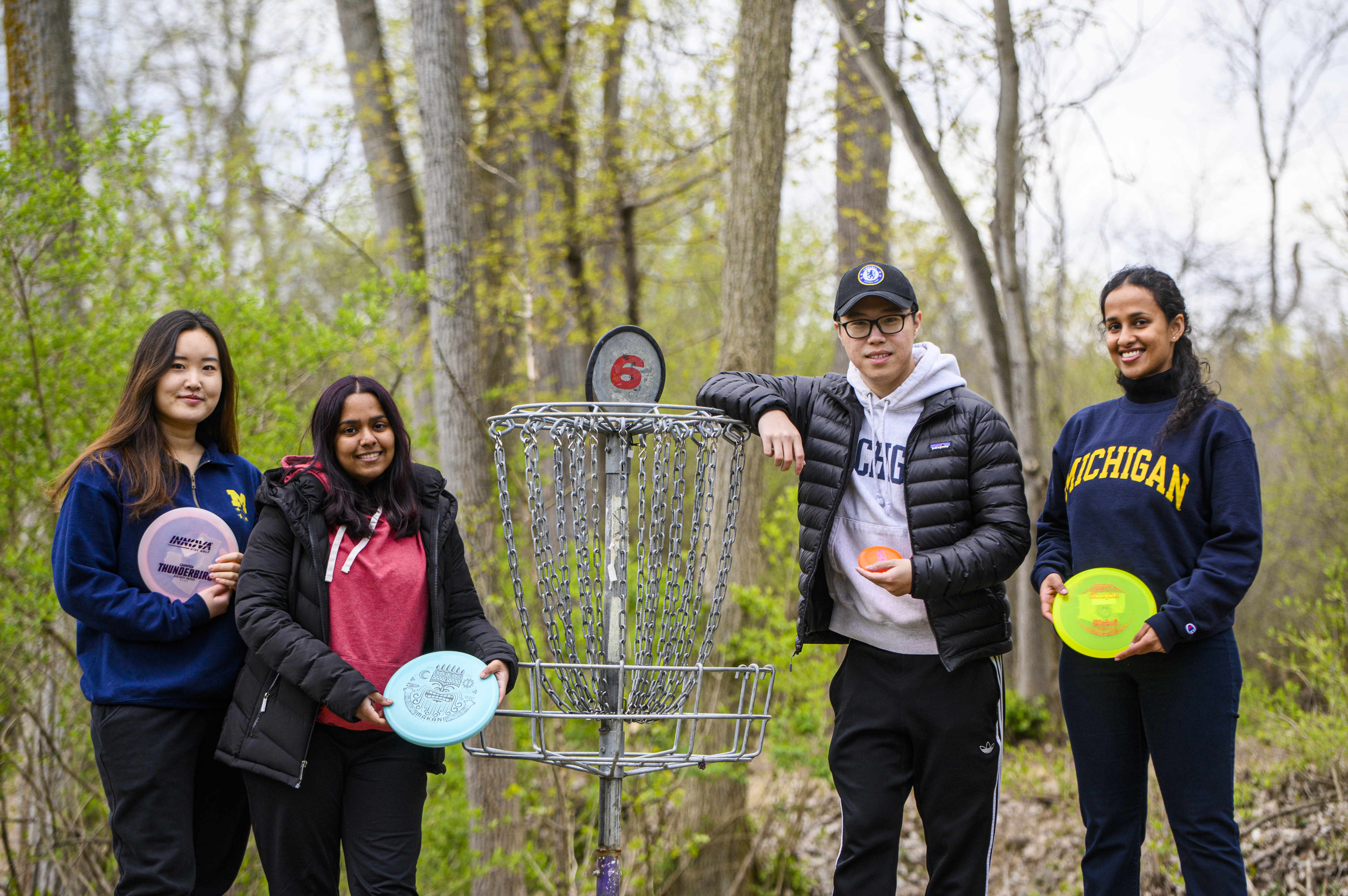 Four people stand in the woods at a disc golf course