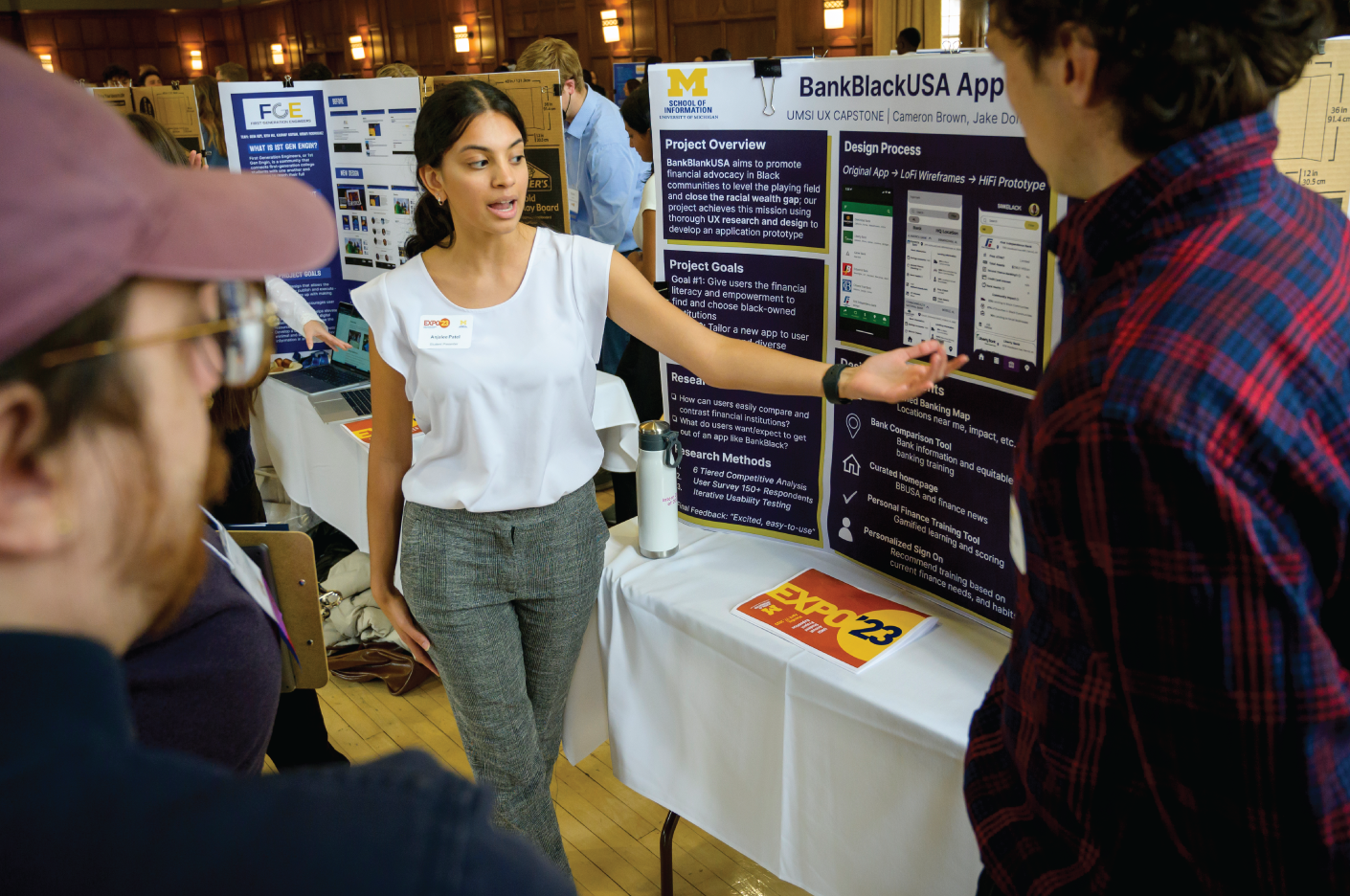 A student pointing to a research poster and talking to two others