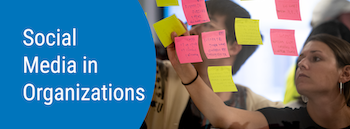 Social Media in Organizations. People placing sticky notes on a clear wall.