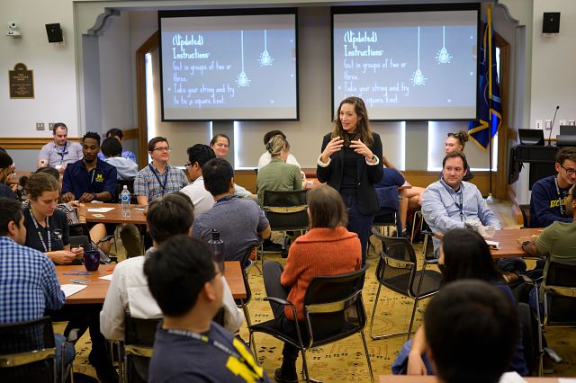 A person giving a presentation to a group of people who are sitting at tables.