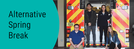 Alternative Spring Break. Four students standing on the back of a fire truck.