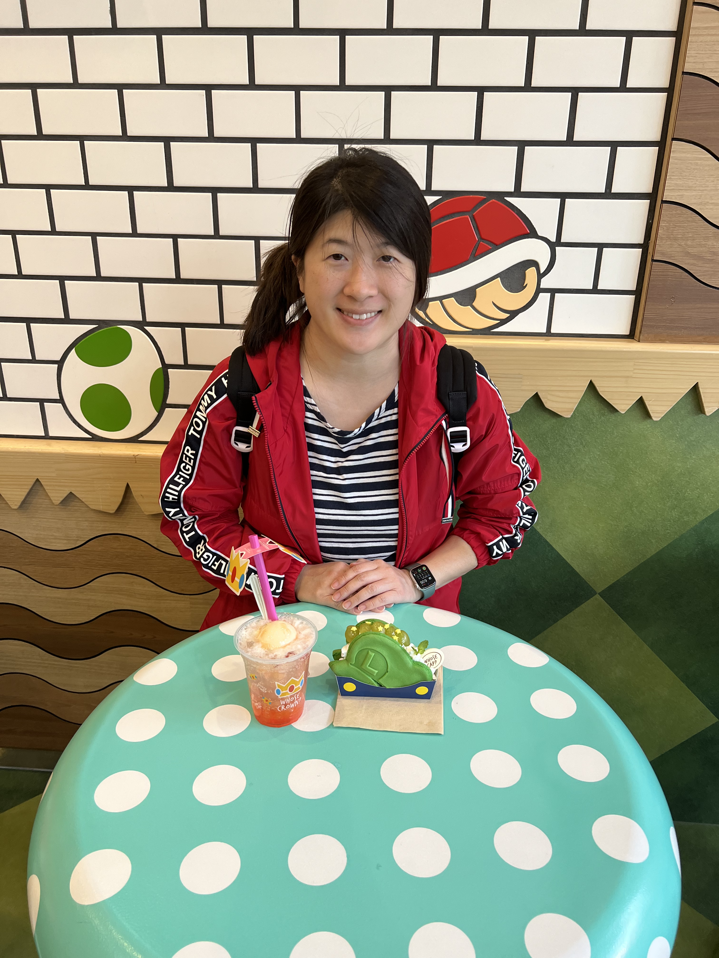 Natalie Fang seated at a blue polka dot table holding a beverage and treat at Nintendo's Mario Café