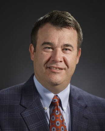 Headshot of Randy Riley, state librarian of Michigan, smiling and wearing a suit coat and a red tie