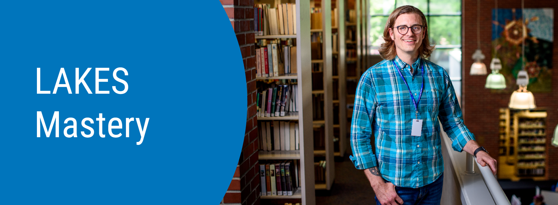 LAKES Mastery. A person standing next to bookshelves in a library.