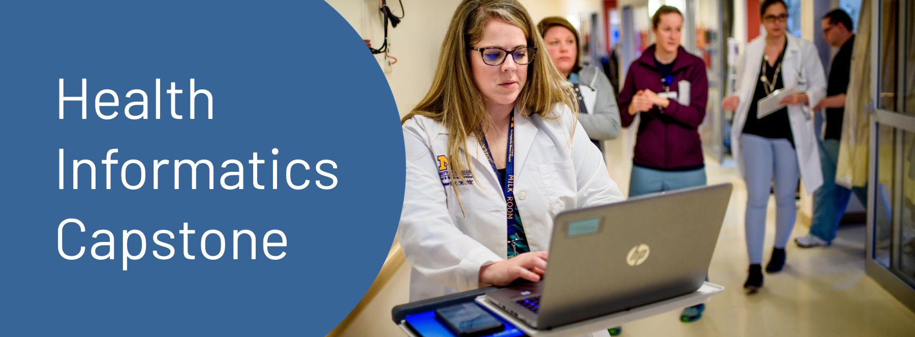 Health Informatics Capstone. A person in a white doctor coat using a laptop in a hospital.