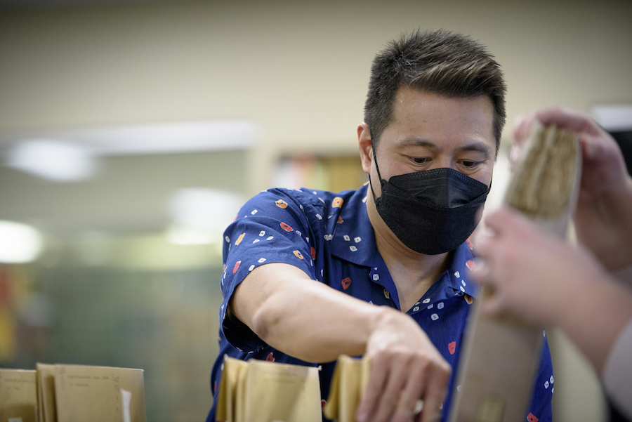 Ricky Punzalan, wearing a KN95 mask, searches through archival materials. 
