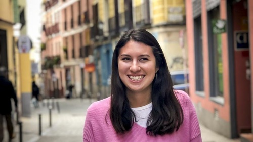 Emma Shpiz standing on a colorful cobblestone street in Madrid. 