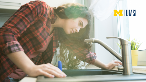 "An image of a person leaning over a sink staring at a faucet. UMSI logo in the corner."