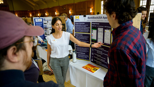 A student discussing a poster with two other people