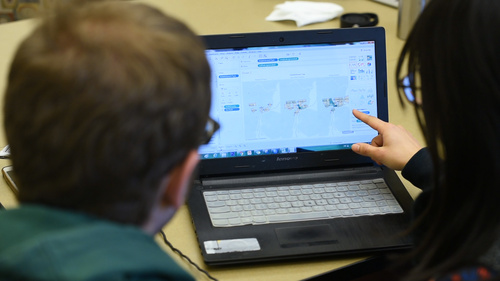 Two people looking at data visualizations on a laptop.