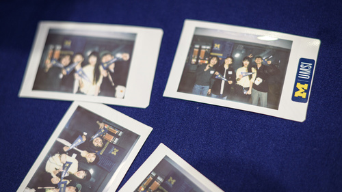Polaroid photos of students holding UMSI pennants