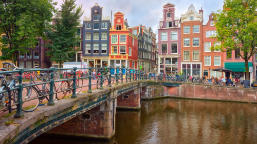 A photo of a bridge over a canal in Amsterdam, lined with bikes