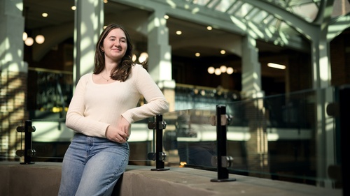 Charlotte Parent poses against a glass railing over the atrium of a building