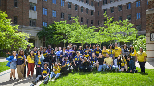 A large group photo in a courtyard in front of an academic building.