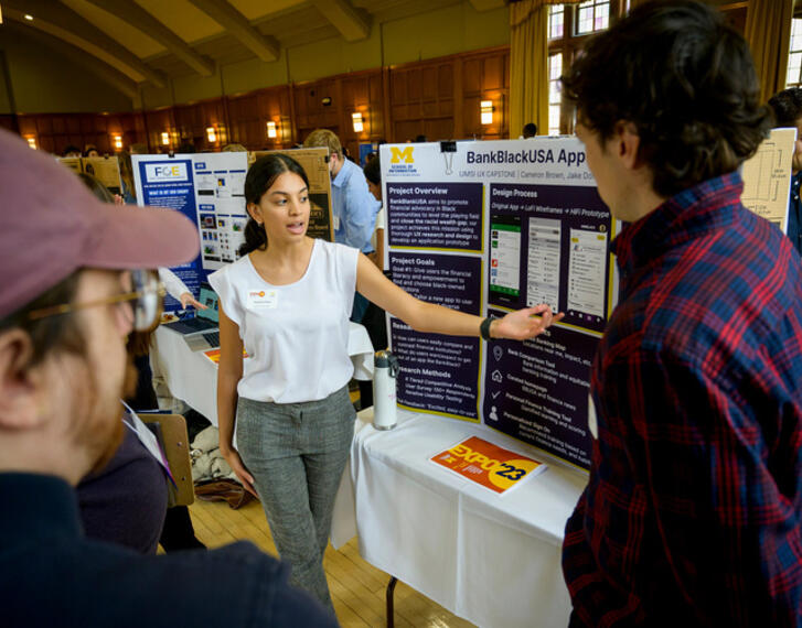 A student discussing a poster with two other people