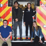 Four students standing on a fire truck