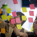 People putting sticky notes up on a transparent wall