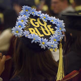 A person wearing a mortar board that says Go Blue with blue flowers all along the edge.