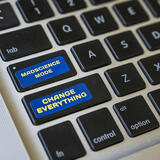 A laptop keyboard with two stickers that say MAD science mode and Change Everything.
