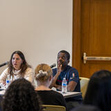 Two people on a panel in front of a crowd.