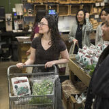 A group of students in a grocery store. One is using a cart. 