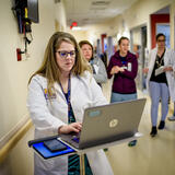 A person in a white doctor coat using a laptop in a hospital