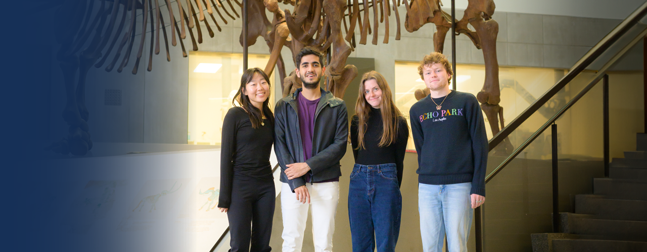 Four students standing in front of an animal skeleton in a museum