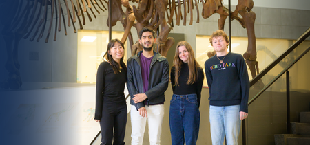 Four students standing in front of an animal skeleton in a museum