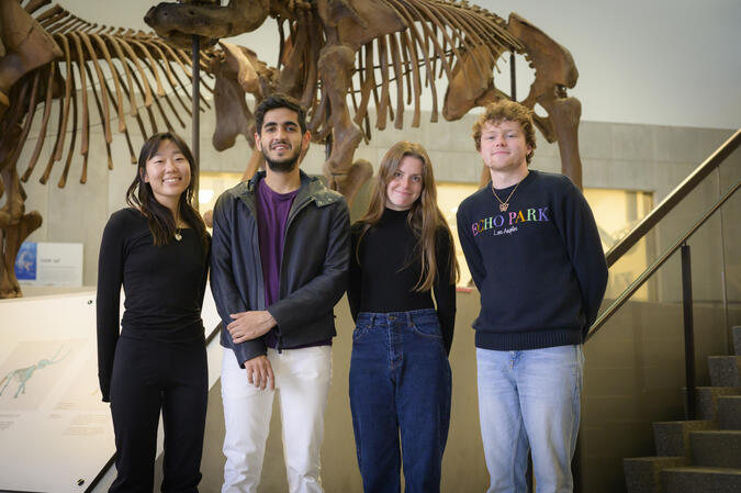 Four students standing in front of an animal skeleton in a museum