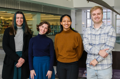 Four students posing together and smiling.