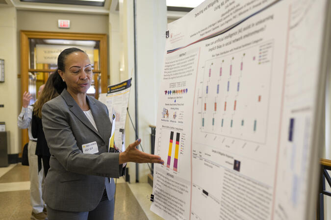 A student talking and gesturing at a research poster.