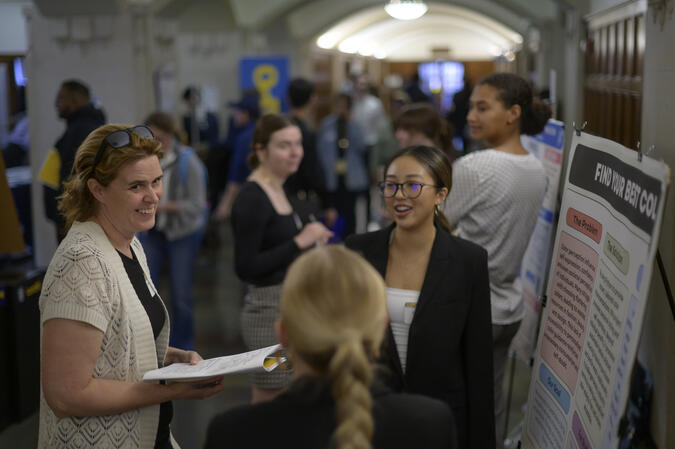 People networking next to a student poster.