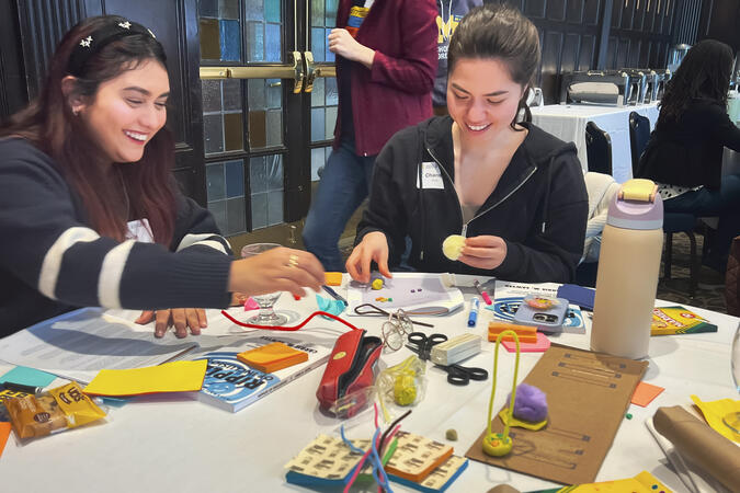 Two students working together at a table with sticky notes and craft supplies.