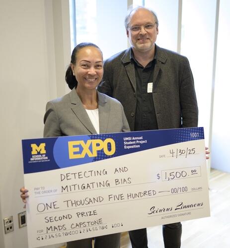 Two people holding a giant check made out to Detecting and Mitigating Bias for $1,500