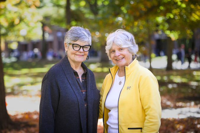 Kenlee Ray and Sue Quackenbush smiling on an autumnal quad wearing dark blue and maize 
