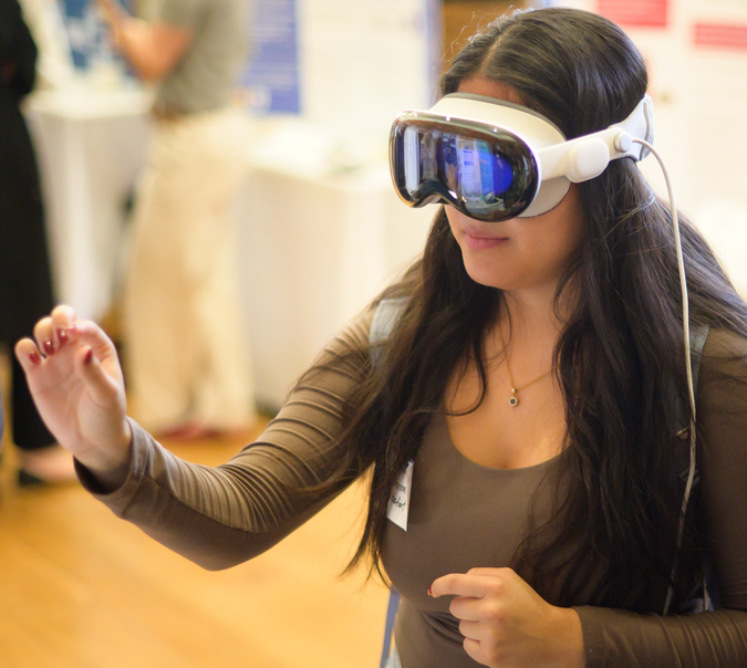 A person wearing a VR headset holding out their hand with their thumb and first finger about half an inch apart.