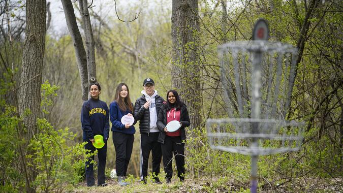Four people stand in the woods at a disc golf course