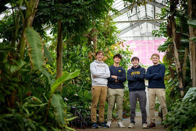 Four students posing together in a greenhouse.