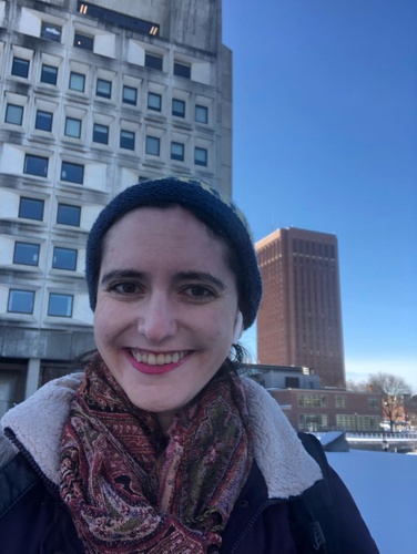 Rebecca Barabas standing outdoors in front of two tall buildings. 