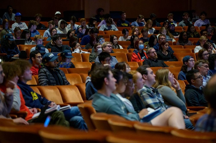 People sit in Rackham Auditorium, facing the stage