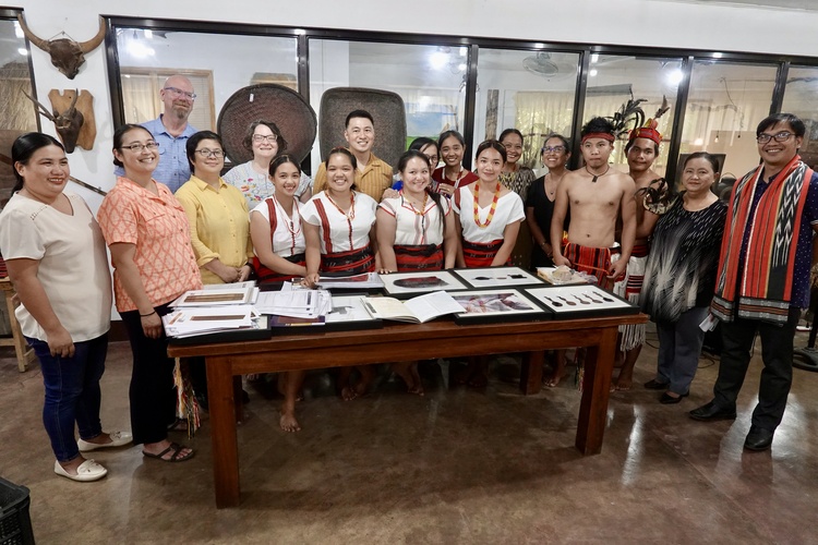 A group poses around a table of artifacts