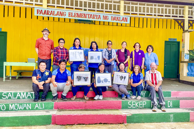 People pose on a colorful staircase holding framed images