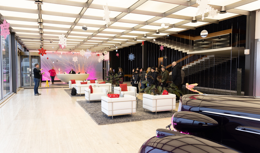 An image of the lobby of GM's design studio. Marc Tarling addresses a group of students, with midcentury modern chairs and part of a classic car in the frame.