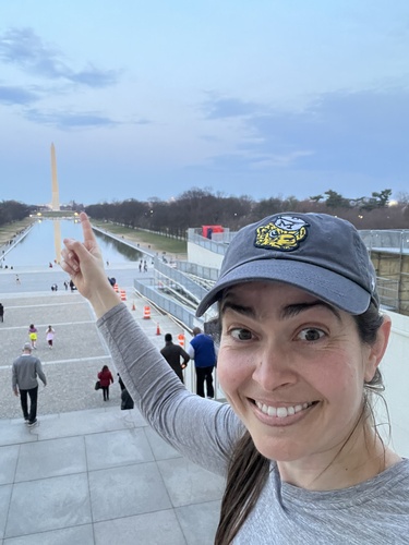 A selfie of Lauralyn Curry-Leech pointing to the Washington Monument