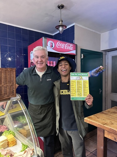 David Diokno holds a laminated restaurant menu while standing beside the owner.