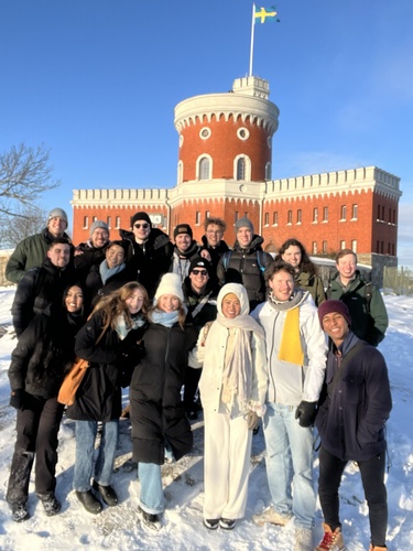 A group of students stand in front of an orange castle in Stockholm.