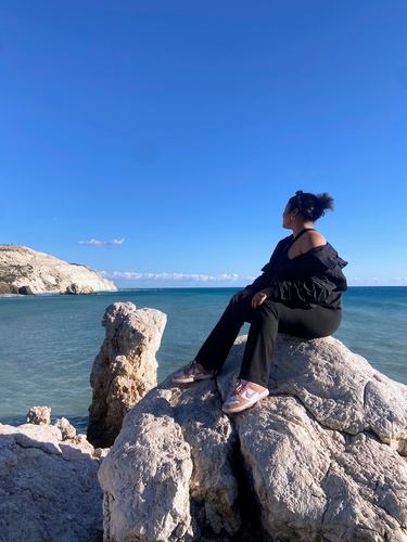 During weekend travels, Yessenia sits on Aphrodite's Rock in Paphos, Cyprus.