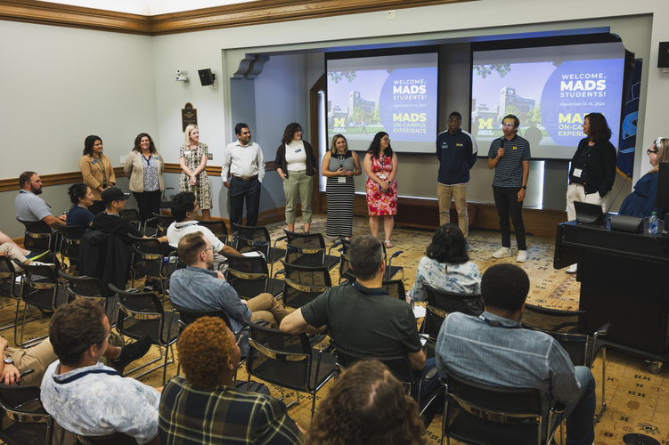 Students gather in an event space filled with single chairs.
