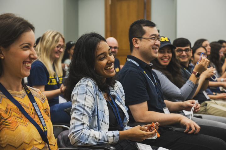 A close-up of students laughing in a small audience. 