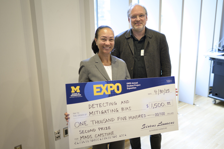 Celia Banks poses, smiling, beside Kevyn Collins-Thompson, holding an award check with an Expo and UMSI logo